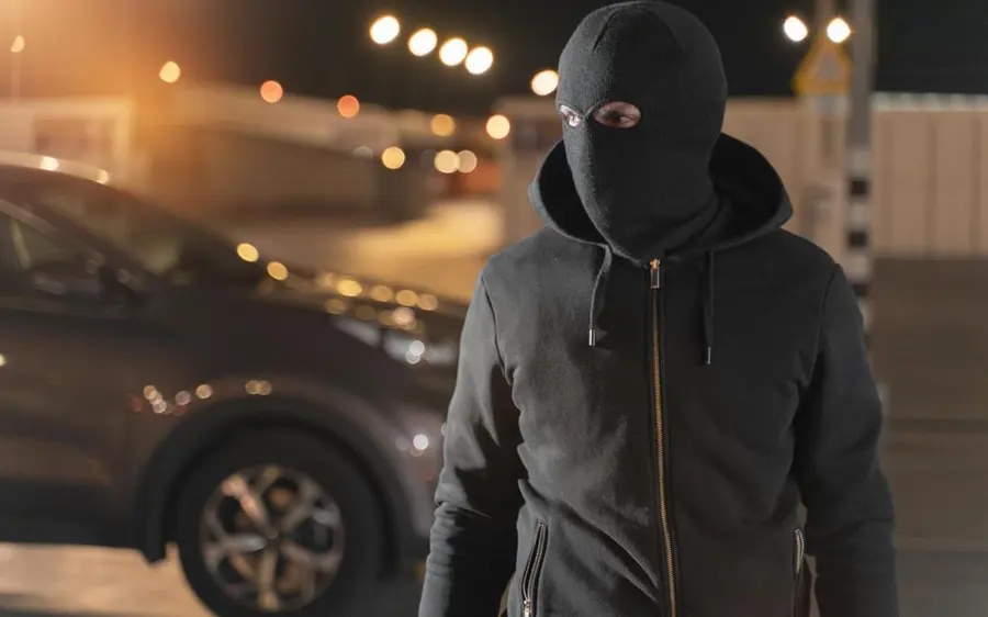 Invasor encapuzado próximo a um veículo à noite